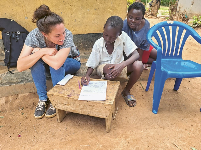 Varinia Dieperink, coopérante d’Eirene Suisse en Ouganda, avec un enfant dont l’écolage était financé par l’un des projets de YOLRED, en train d’écrire une lettre de remerciements. source Photo : Varinia Dieperink, Eirene Suisse