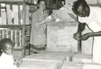 Aperçu Gertrud Schürch, une coopérante de SAM global, et un employé d'une pharmacie déballent ensemble des paquets de médicaments de leurs cartons en Angola. Photo: SAM global (1971).